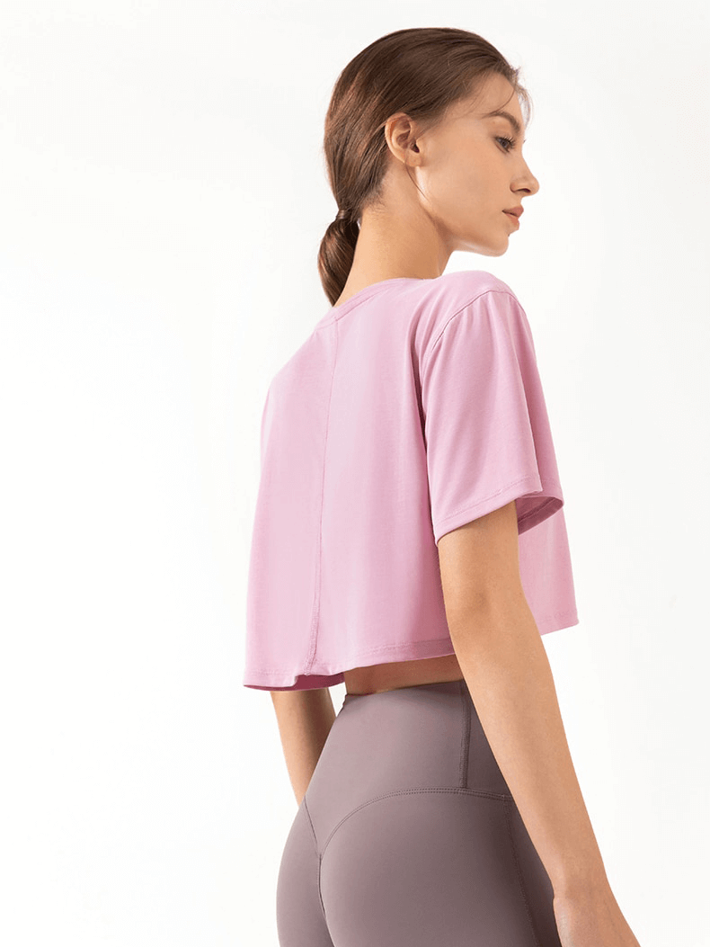 Woman wearing pink ultralight elastic breathable gym T-shirt with short sleeves, perfect for fitness or yoga.